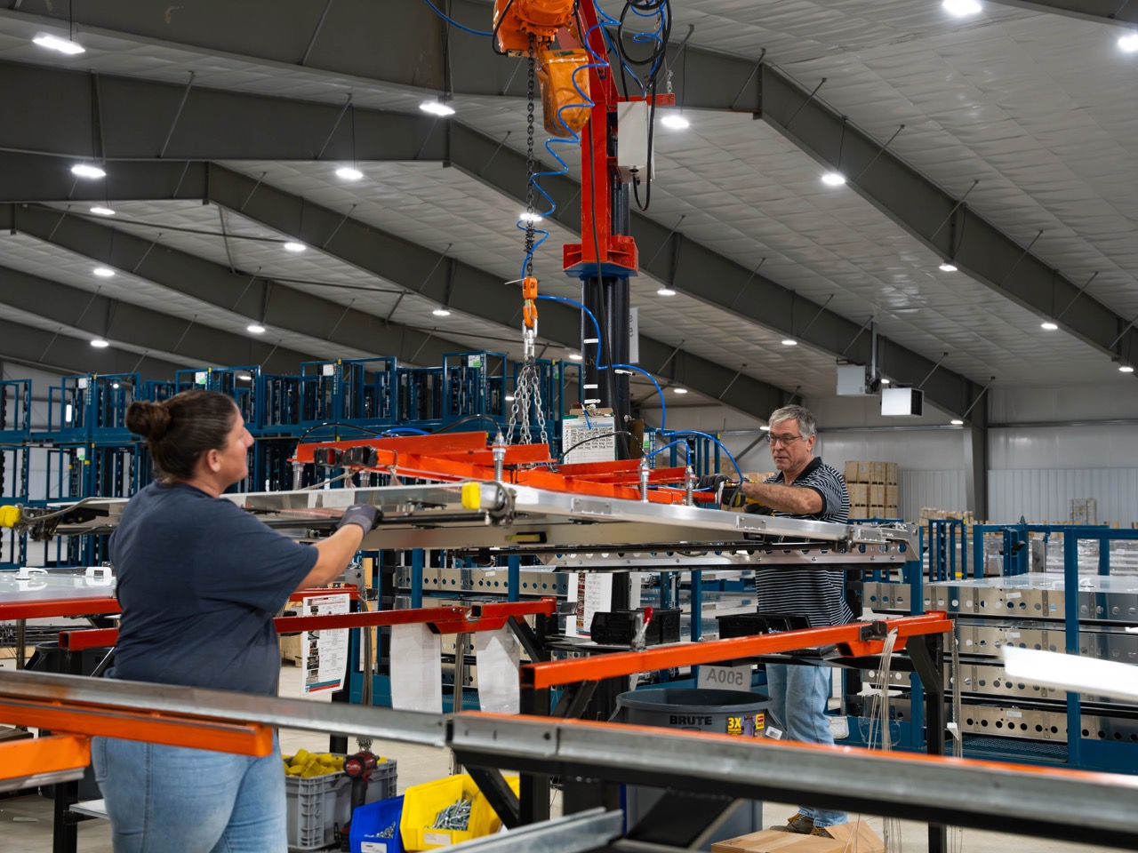 Door element suspended by machine, guided by transglobal employees in warehouse